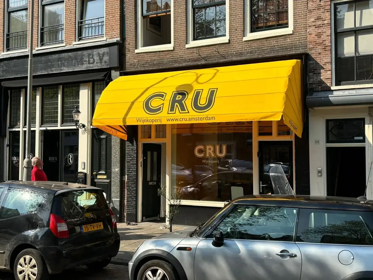 Gele markies met CRU-logo boven wijnkoperij CRU in Amsterdam